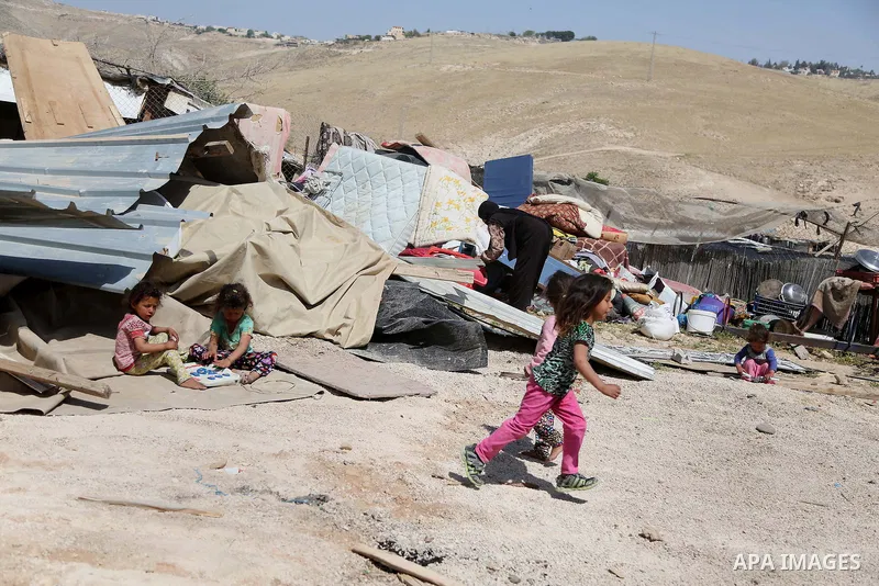 children from the Arab Jahalin Bedouin community play past the debris of homes in the West Bank Bedouin camp of al-Khan al-Ahmar on April 7, 2016 after Israeli authorities demolished four houses that they said were built...