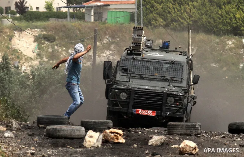 A Palestinian protester hurls stones towards Israeli security forces jeep during clashes following a weekly demonstration against the expropriation of Palestinian land by Israel in the village of Kfar Qaddum, near Nablus...