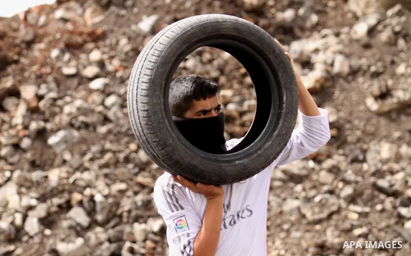 A Palestinian protester carries tires during clashes with Israeli security forces following a weekly demonstration against the expropriation of Palestinian land by Israel in the village of Kfar Qaddum, near Nablus, in th...
