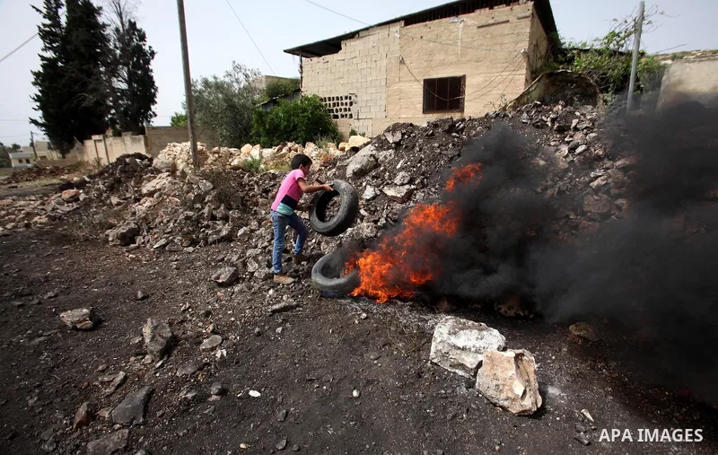 A Palestinian protester burns tires during clashes with Israeli security forces following a weekly demonstration against the expropriation of Palestinian land by Israel in the village of Kfar Qaddum, near Nablus, in the...