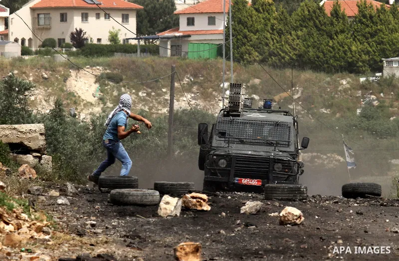 A Palestinian protester hurls stones towards Israeli security forces jeep during clashes following a weekly demonstration against the expropriation of Palestinian land by Israel in the village of Kfar Qaddum, near Nablus...