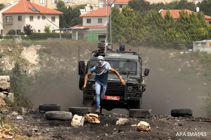 A Palestinian protester runs for cover from an Israeli security jeep during clashes following a weekly demonstration against the expropriation of Palestinian land by Israel in the village of Kfar Qaddum, near Nablus, in...