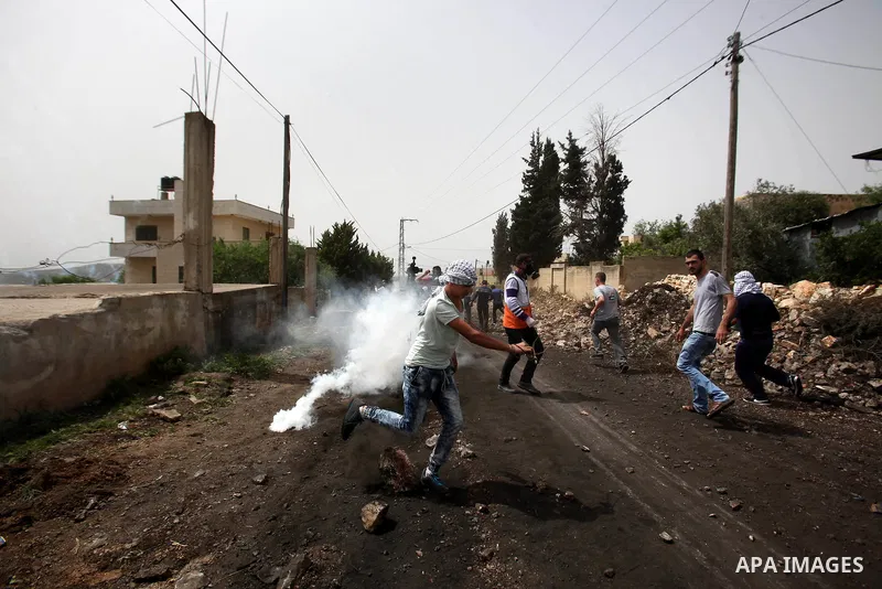 Palestinian protesters run for cover from tear gas fired by Israeli security forces during clashes following a weekly demonstration against the expropriation of Palestinian land by Israel in the village of Kfar Qaddum, n...