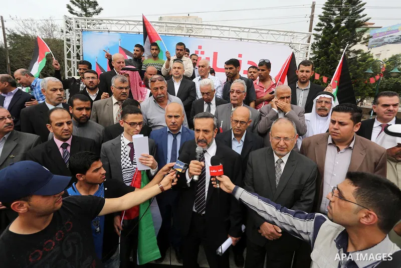 Palestinians hold national flags during a demonstration to calling for an end in the political division and the national reconciliation in Gaza city, on April 10, 2016. Photo by Mohammed Asad
