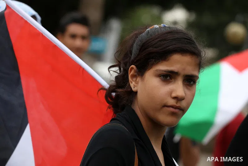 Palestinians hold national flags during a demonstration to calling for an end in the political division and the national reconciliation in Gaza city, on April 10, 2016. Photo by Mohammed Asad
