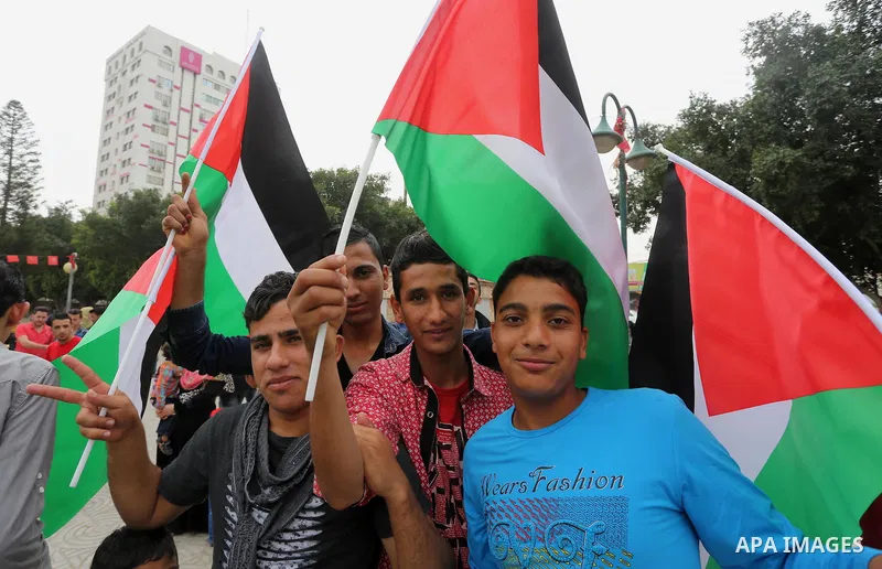 Palestinians hold national flags during a demonstration to calling for an end in the political division and the national reconciliation in Gaza city, on April 10, 2016. Photo by Mohammed Asad