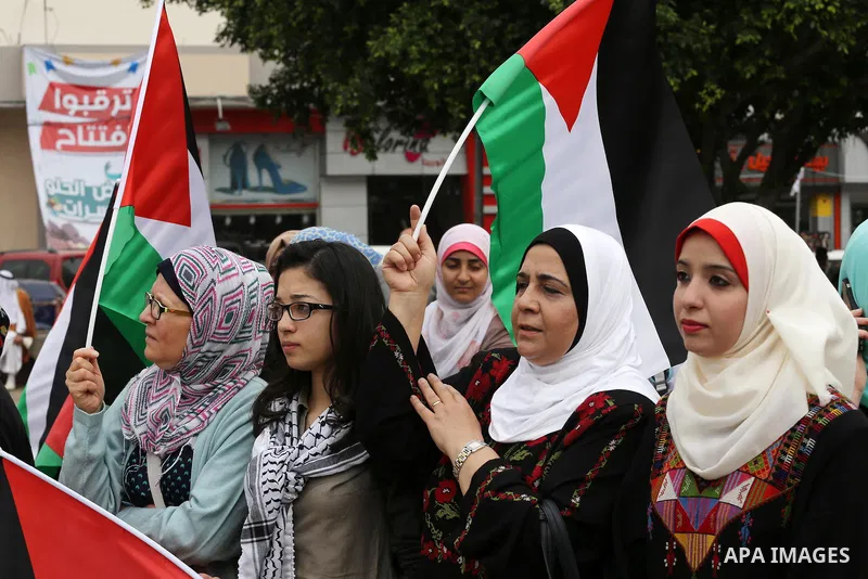 Palestinians hold national flags during a demonstration to calling for an end in the political division and the national reconciliation in Gaza city, on April 10, 2016. Photo by Mohammed Asad