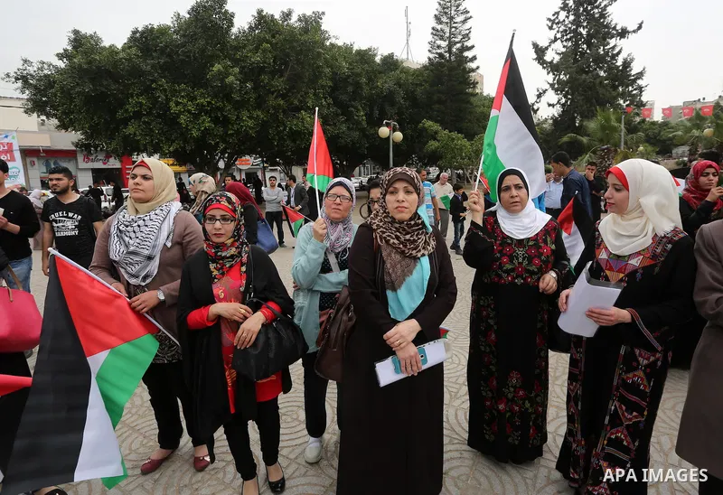 Palestinians hold national flags during a demonstration to calling for an end in the political division and the national reconciliation in Gaza city, on April 10, 2016. Photo by Mohammed Asad