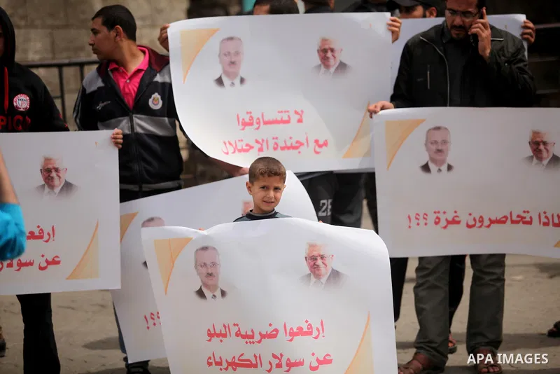 Palestinians hold banners during a protest against a power cut, in front of the Council of Ministers, in Gaza city, on April 11, 2016. Photo by Ashraf Amra