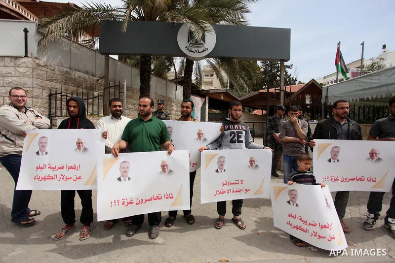 Palestinians hold banners during a protest against a power cut, in front of the Council of Ministers, in Gaza city, on April 11, 2016. Photo by Ashraf Amra