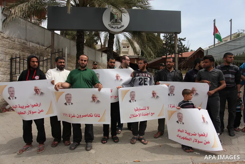 Palestinians hold banners during a protest against a power cut, in front of the Council of Ministers, in Gaza city, on April 11, 2016. Photo by Ashraf Amra
