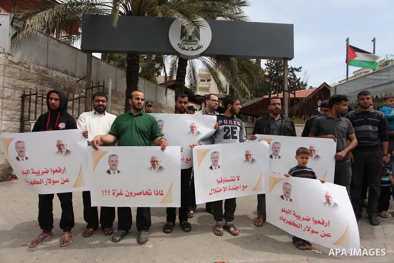 Palestinians hold banners during a protest against a power cut, in front of the Council of Ministers, in Gaza city, on April 11, 2016. Photo by Ashraf Amra