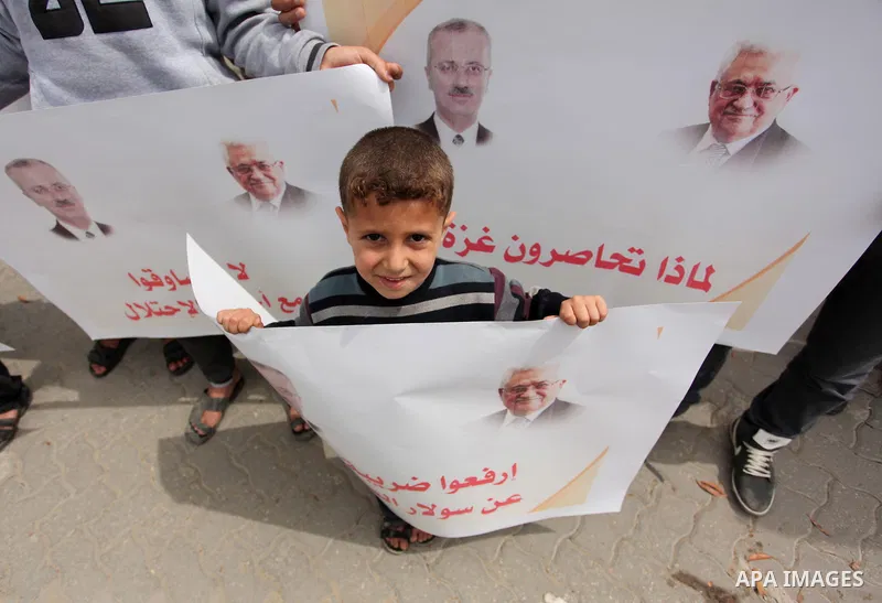 Palestinians hold banners during a protest against a power cut, in front of the Council of Ministers, in Gaza city, on April 11, 2016. Photo by Ashraf Amra