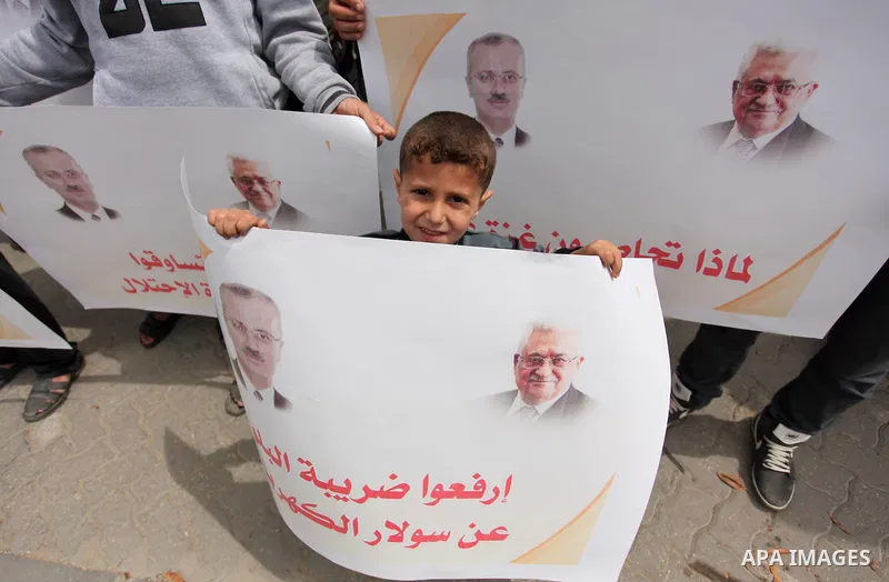 Palestinians hold banners during a protest against a power cut, in front of the Council of Ministers, in Gaza city, on April 11, 2016. Photo by Ashraf Amra
