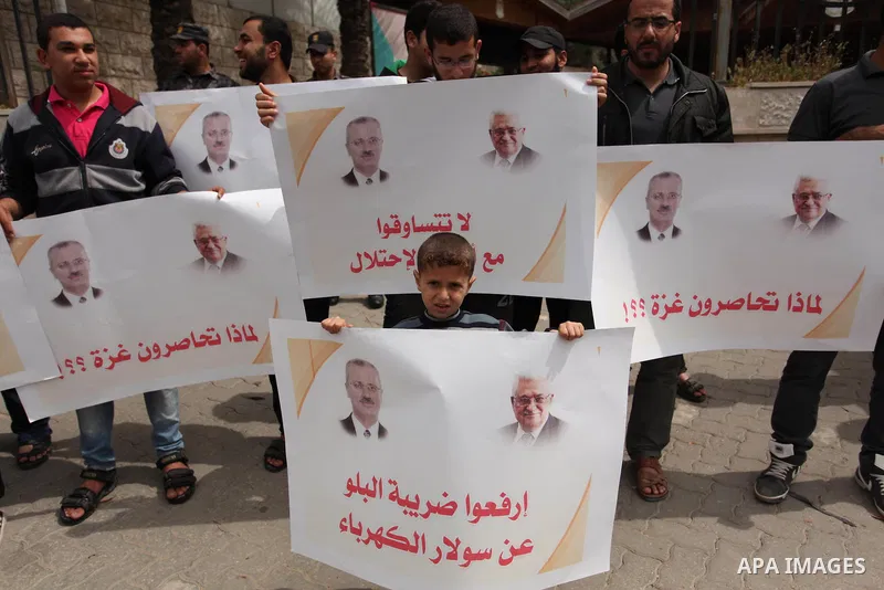 Palestinians hold banners during a protest against a power cut, in front of the Council of Ministers, in Gaza city, on April 11, 2016. Photo by Ashraf Amra