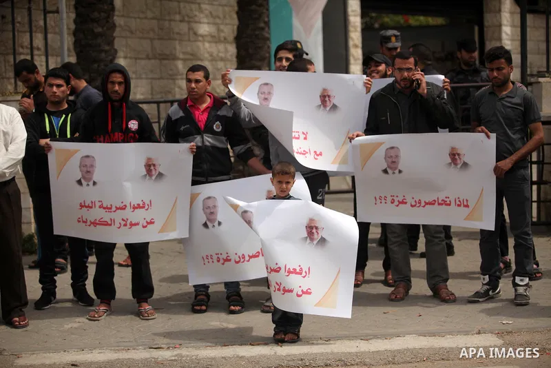 Palestinians hold banners during a protest against a power cut, in front of the Council of Ministers, in Gaza city, on April 11, 2016. Photo by Ashraf Amra