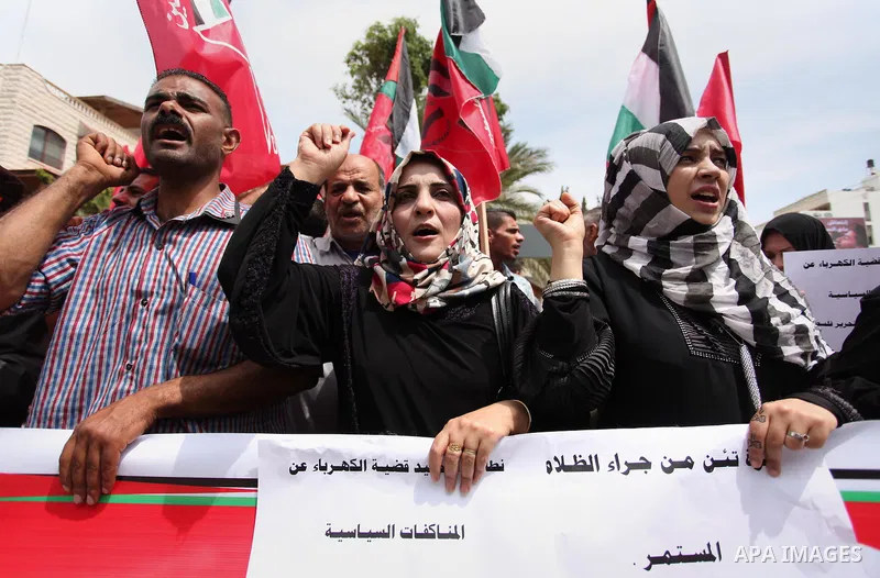 Palestinian supporters of the Democratic Front for the Liberation of Palestine (DFLP) shout slogans and hold banners during a protest against a power cut, in front of the Council of Ministers, in Gaza city, on April 11,...