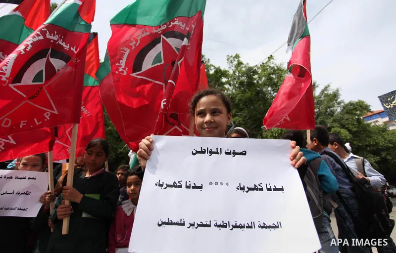 Palestinian supporters of the Democratic Front for the Liberation of Palestine (DFLP) shout slogans and hold banners during a protest against a power cut, in front of the Council of Ministers, in Gaza city, on April 11,...