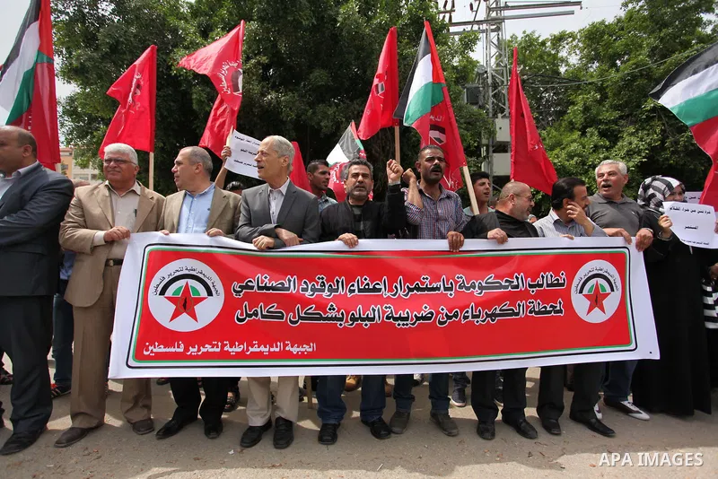 Palestinian supporters of the Democratic Front for the Liberation of Palestine (DFLP) shout slogans and hold banners during a protest against a power cut, in front of the Council of Ministers, in Gaza city, on April 11,...