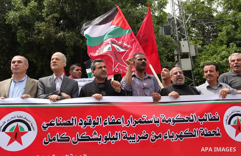 Palestinian supporters of the Democratic Front for the Liberation of Palestine (DFLP) shout slogans and hold banners during a protest against a power cut, in front of the Council of Ministers, in Gaza city, on April 11,...