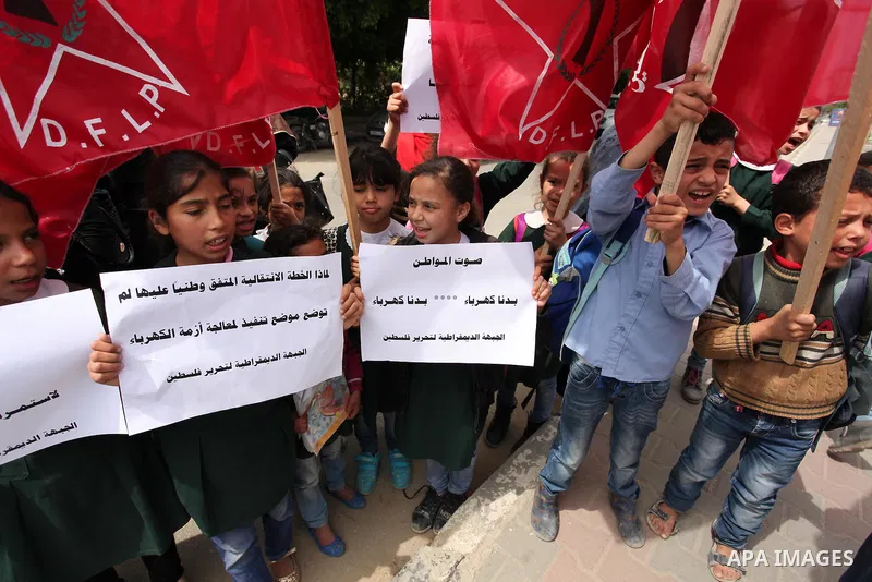Palestinian supporters of the Democratic Front for the Liberation of Palestine (DFLP) shout slogans and hold banners during a protest against a power cut, in front of the Council of Ministers, in Gaza city, on April 11,...