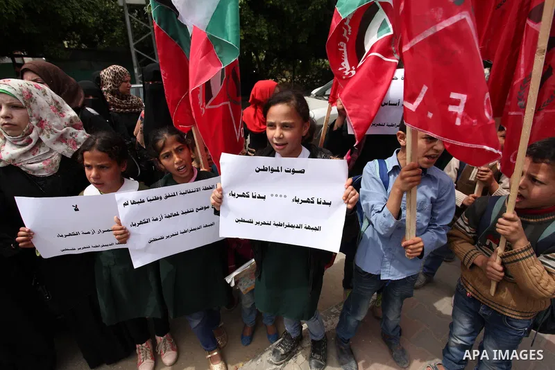 Palestinian supporters of the Democratic Front for the Liberation of Palestine (DFLP) shout slogans and hold banners during a protest against a power cut, in front of the Council of Ministers, in Gaza city, on April 11,...