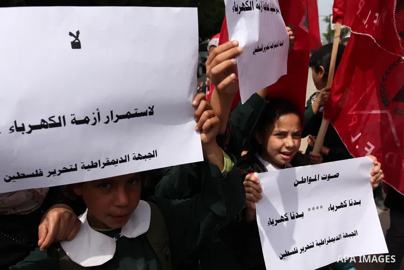 Palestinian supporters of the Democratic Front for the Liberation of Palestine (DFLP) shout slogans and hold banners during a protest against a power cut, in front of the Council of Ministers, in Gaza city, on April 11,...
