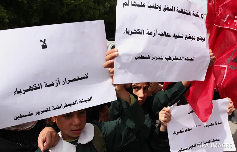 Palestinian supporters of the Democratic Front for the Liberation of Palestine (DFLP) shout slogans and hold banners during a protest against a power cut, in front of the Council of Ministers, in Gaza city, on April 11,...