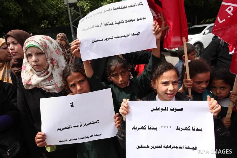 Palestinian supporters of the Democratic Front for the Liberation of Palestine (DFLP) shout slogans and hold banners during a protest against a power cut, in front of the Council of Ministers, in Gaza city, on April 11,...