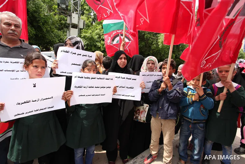 Palestinian supporters of the Democratic Front for the Liberation of Palestine (DFLP) shout slogans and hold banners during a protest against a power cut, in front of the Council of Ministers, in Gaza city, on April 11,...