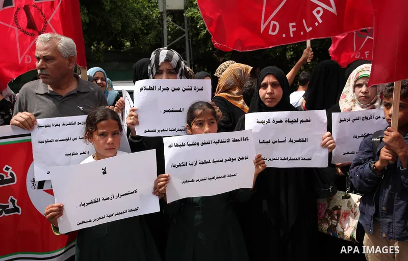 Palestinian supporters of the Democratic Front for the Liberation of Palestine (DFLP) shout slogans and hold banners during a protest against a power cut, in front of the Council of Ministers, in Gaza city, on April 11,...