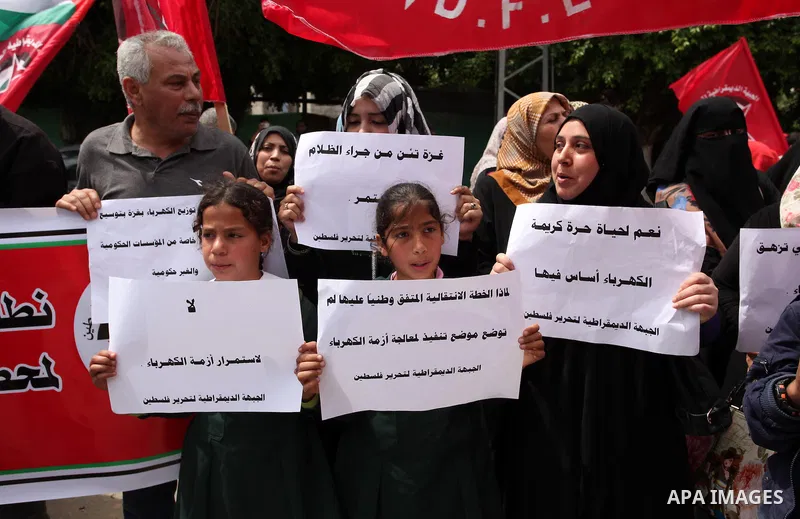 Palestinian supporters of the Democratic Front for the Liberation of Palestine (DFLP) shout slogans and hold banners during a protest against a power cut, in front of the Council of Ministers, in Gaza city, on April 11,...
