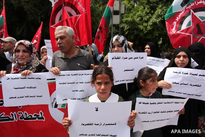 Palestinian supporters of the Democratic Front for the Liberation of Palestine (DFLP) shout slogans and hold banners during a protest against a power cut, in front of the Council of Ministers, in Gaza city, on April 11,...