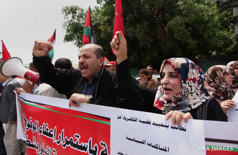 Palestinian supporters of the Democratic Front for the Liberation of Palestine (DFLP) shout slogans and hold banners during a protest against a power cut, in front of the Council of Ministers, in Gaza city, on April 11,...