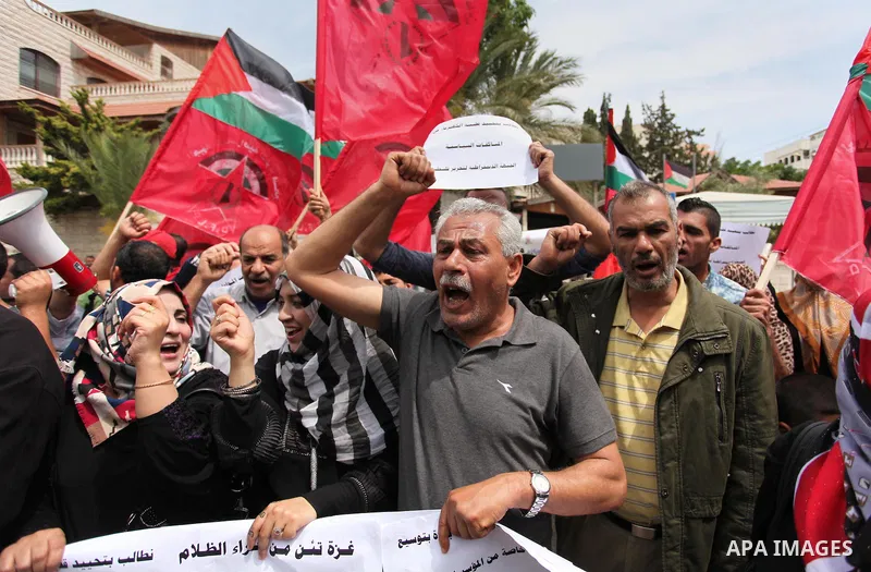 Palestinian supporters of the Democratic Front for the Liberation of Palestine (DFLP) shout slogans and hold banners during a protest against a power cut, in front of the Council of Ministers, in Gaza city, on April 11,...