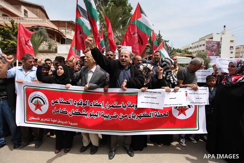 Palestinian supporters of the Democratic Front for the Liberation of Palestine (DFLP) shout slogans and hold banners during a protest against a power cut, in front of the Council of Ministers, in Gaza city, on April 11,...