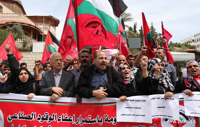 Palestinian supporters of the Democratic Front for the Liberation of Palestine (DFLP) shout slogans and hold banners during a protest against a power cut, in front of the Council of Ministers, in Gaza city, on April 11,...