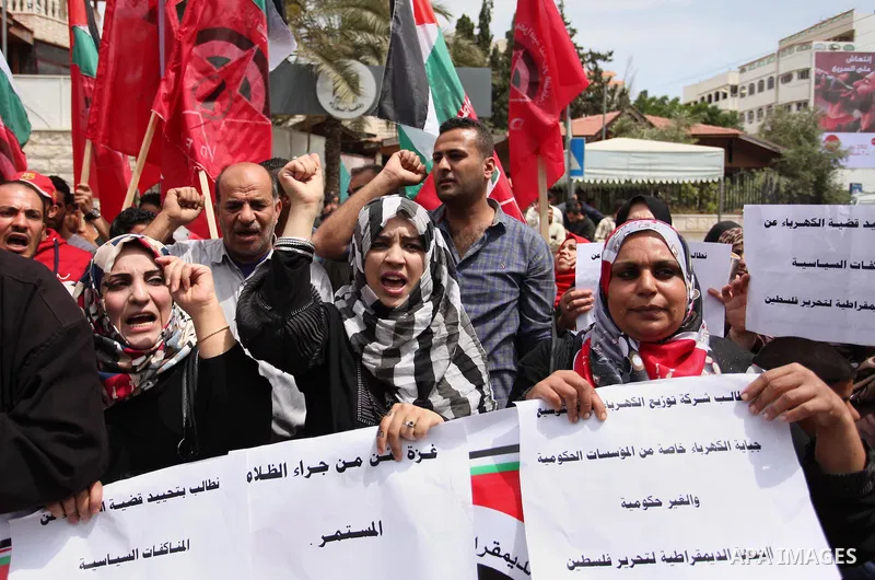 Palestinian supporters of the Democratic Front for the Liberation of Palestine (DFLP) shout slogans and hold banners during a protest against a power cut, in front of the Council of Ministers, in Gaza city, on April 11,...