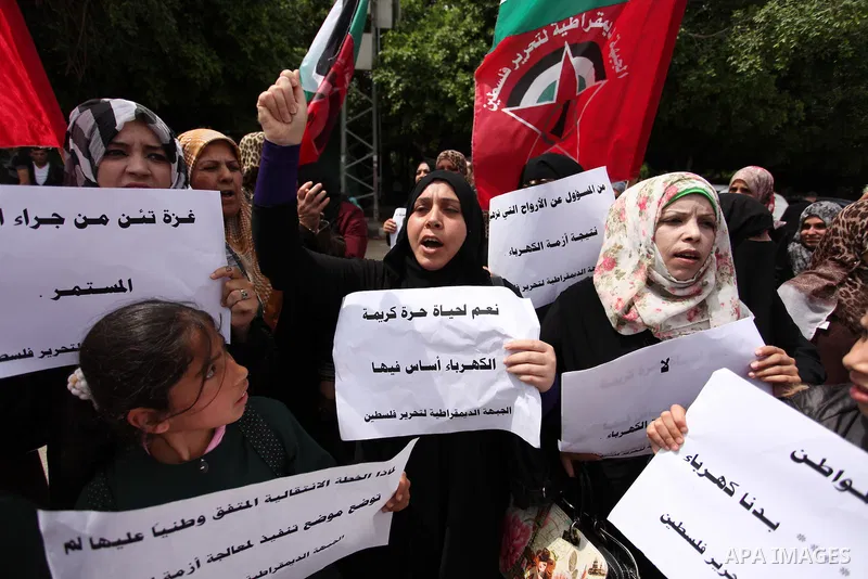 Palestinian supporters of the Democratic Front for the Liberation of Palestine (DFLP) shout slogans and hold banners during a protest against a power cut, in front of the Council of Ministers, in Gaza city, on April 11,...