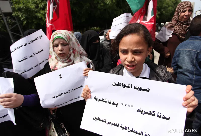 Palestinian supporters of the Democratic Front for the Liberation of Palestine (DFLP) shout slogans and hold banners during a protest against a power cut, in front of the Council of Ministers, in Gaza city, on April 11,...