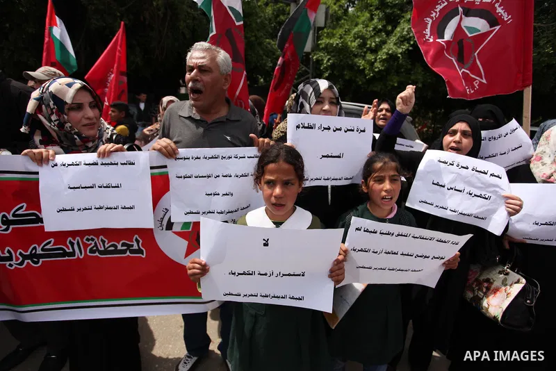 Palestinian supporters of the Democratic Front for the Liberation of Palestine (DFLP) shout slogans and hold banners during a protest against a power cut, in front of the Council of Ministers, in Gaza city, on April 11,...