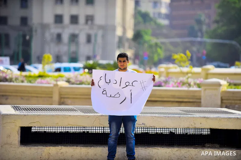 An Egyptian protester holds placard wrote in arabic "Awwad sold his land" at Tahrir square in Cairo on April 11, 2016. Egypt and Saudi Arabia agreed to maritime borders that handed ownership of disputed Red Sea islands T...