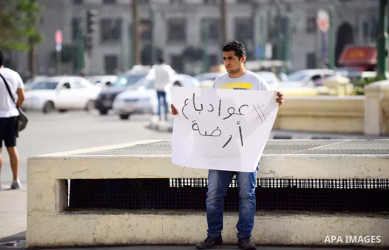 An Egyptian protester holds placard wrote in arabic "Awwad sold his land" at Tahrir square in Cairo on April 11, 2016. Egypt and Saudi Arabia agreed to maritime borders that handed ownership of disputed Red Sea islands T...