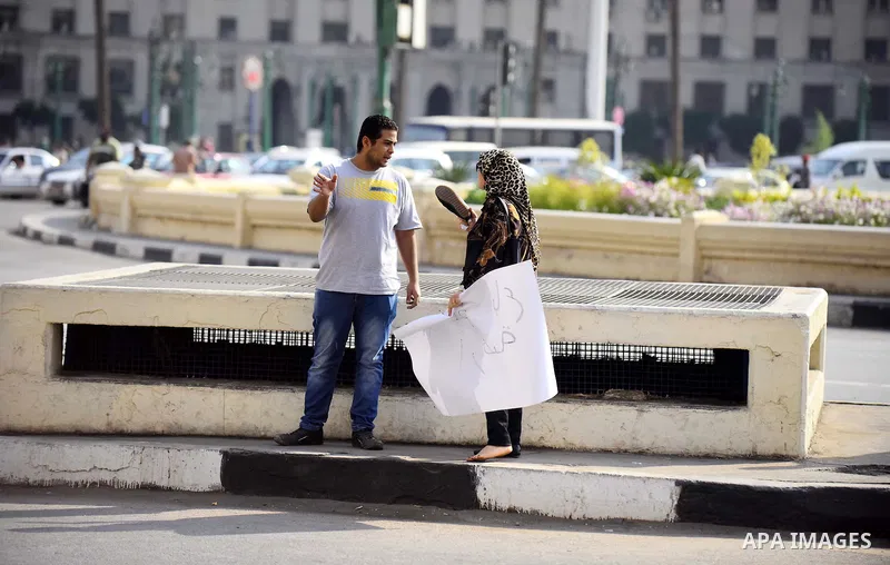 An Egyptian woman argue with an Egyptian protester as he holds placard wrote in arabic "Awwad sold his land" at Tahrir square in Cairo on April 11, 2016. Egypt and Saudi Arabia agreed to maritime borders that handed owne...