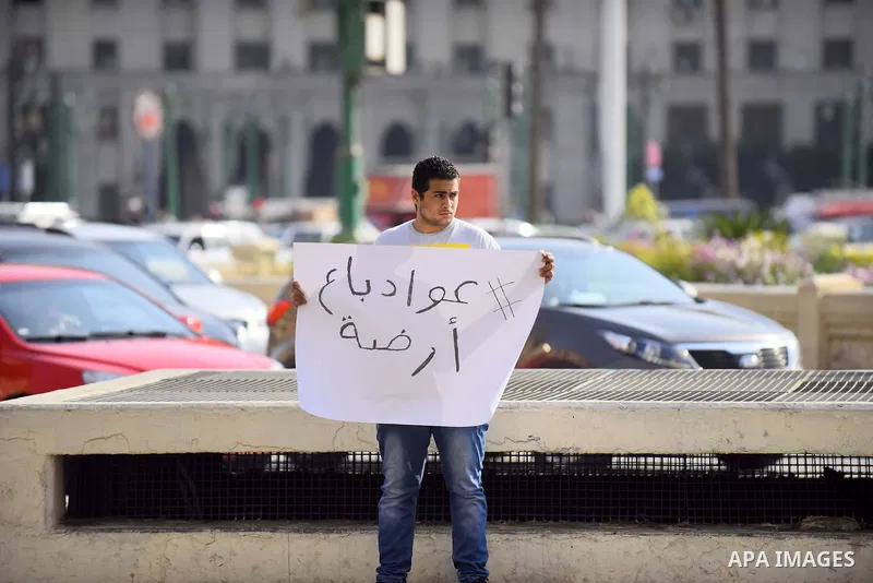 An Egyptian protester holds placard wrote in arabic "Awwad sold his land" at Tahrir square in Cairo on April 11, 2016. Egypt and Saudi Arabia agreed to maritime borders that handed ownership of disputed Red Sea islands T...