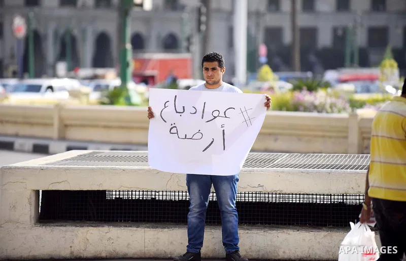 An Egyptian protester holds placard wrote in arabic "Awwad sold his land" at Tahrir square in Cairo on April 11, 2016. Egypt and Saudi Arabia agreed to maritime borders that handed ownership of disputed Red Sea islands T...