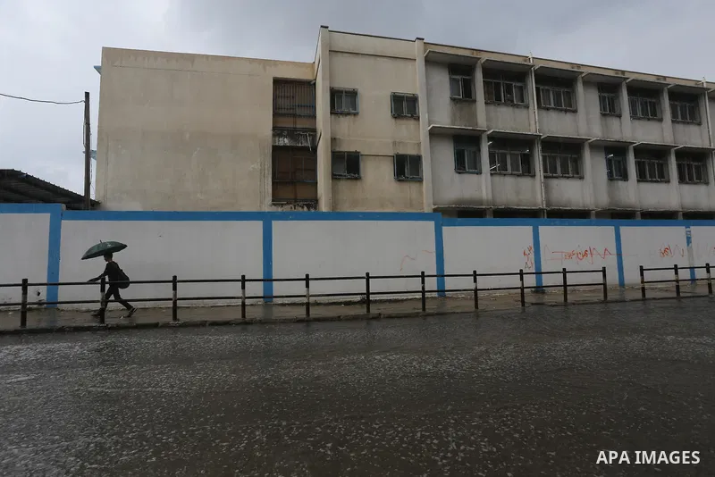 Palestinians walk in a flooded street during a rainy day, in Gaza City on April 12, 2016. Photo by Mohammed Asad