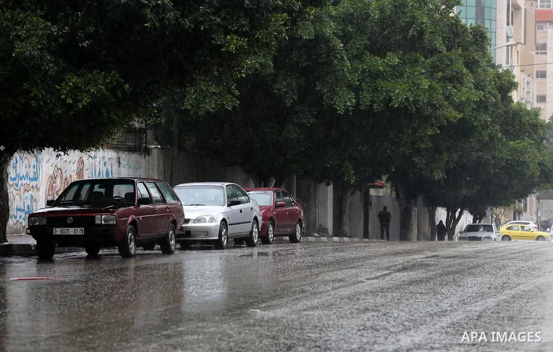 Palestinians walk in a flooded street during a rainy day, in Gaza City on April 12, 2016. Photo by Mohammed Asad