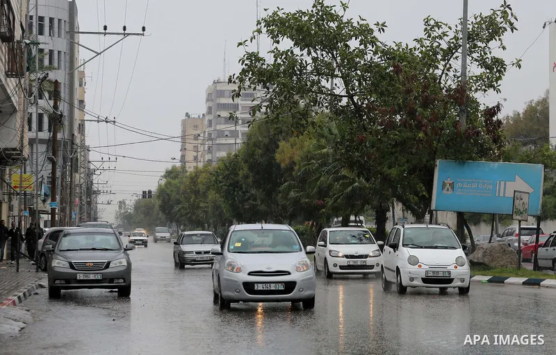 Palestinians walk in a flooded street during a rainy day, in Gaza City on April 12, 2016. Photo by Mohammed Asad