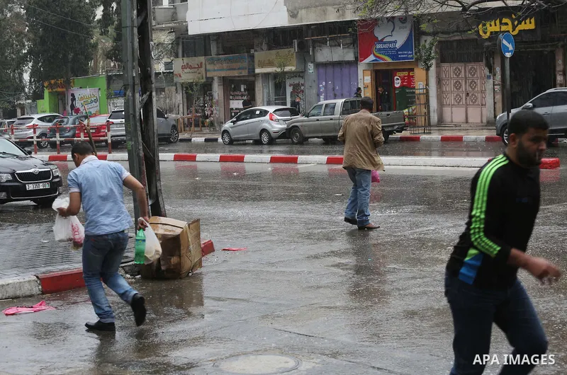Palestinians walk in a flooded street during a rainy day, in Gaza City on April 12, 2016. Photo by Mohammed Asad